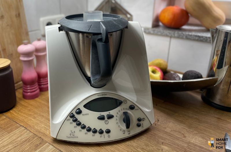 Thermomix TM31 mit Gemüse und Küchenutensilien im Hintergrund